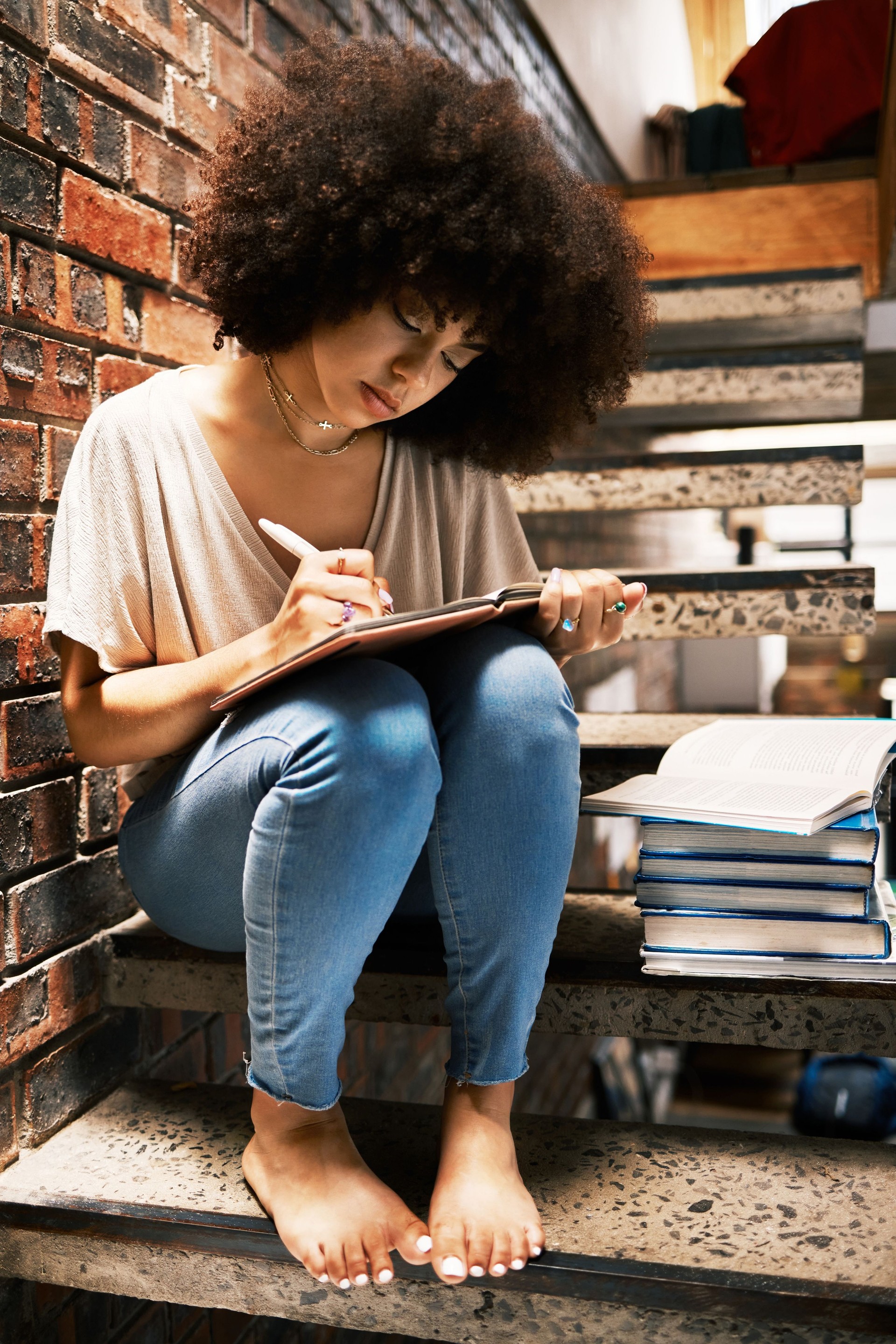 Learning, studying and black woman writing notes in a book, notebook or textbook on house steps. African girl, education and student with notepad, paper or books with a pen or pencil at home.